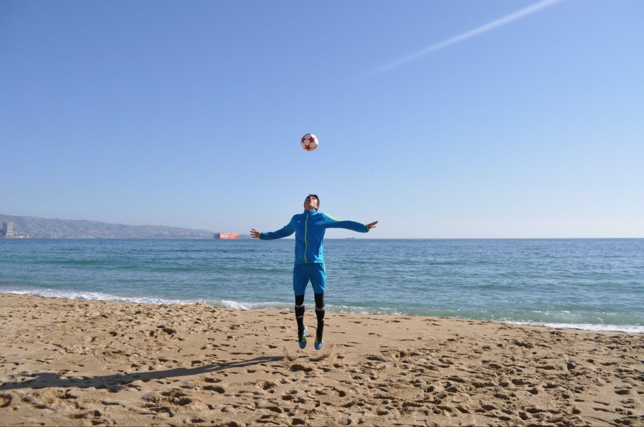Corpo em movimento com bola na praia